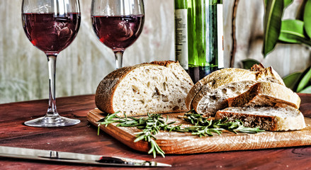 Wine in a glass, bread chiabatta and rosemary on a wooden table. The concept: sadness, loneliness