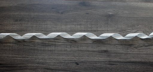 Sparkle silver ribbon on dark wooden background