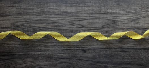 Sparkle golden ribbon on dark wooden background