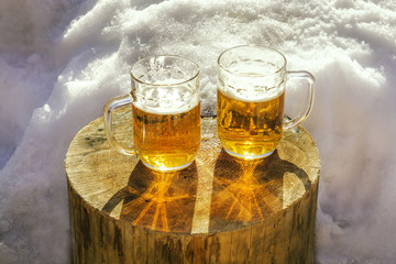 two  beer mugs on the wooden table  on snow