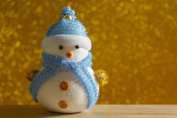 Happy snowman standing in gold winter christmas snow background. Merry christmas and happy new year greeting card with copy-space. Christmas celebration holiday background.