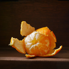 Peeled mandarin on a wooden dark background. Fruit of tangerine without skin. Soft side light on the dark. Healthy eating concept, vegetarian, vegetable healthy food.