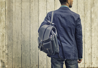 Man in blue suit and jeans with leather backpack