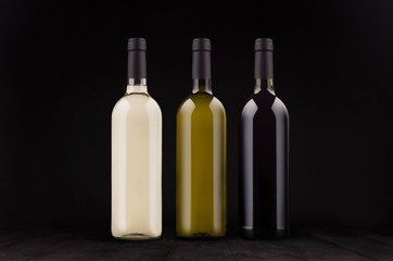 Fototapeta na wymiar Wine bottles set - red, green, white - mock up on elegant dark black wooden background.