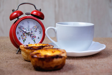Red alarm clock, cup of coffee and Portuguese Custard Tarts, called - Powered by Adobe