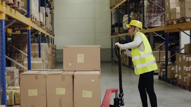 Female warehouse worker with hand forklift truck.