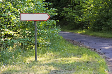 Old road direction sign standing in the woods by the road.
