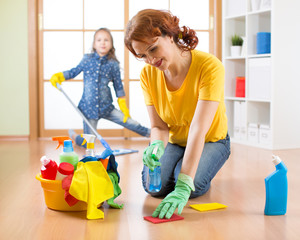 Mother with daughter dusting together at home
