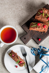 Traditional Christmas dessert, Christmas yule log cake with chocolate cream, cranberry and rosemary twigs. With Christmas tree branches, gifts and decorations, copy space