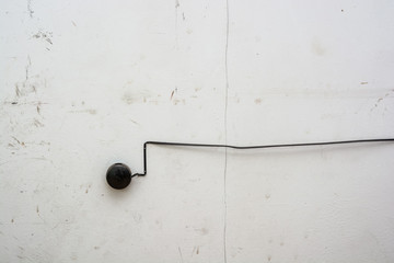 Old black fire alarm detector on white wall