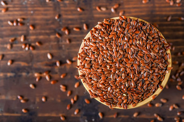 Close up linseed in wooden bowl on wooden table - obrazy, fototapety, plakaty