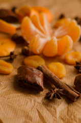 Fototapeta premium christmas concept - mandarin without the skin, spices, skin of an orange, stars of anise, cinnamone, dried fruit on the parchment on the table