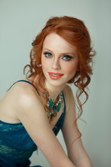 beautiful slender girl with red hair with makeup and haircut in a smart shirt