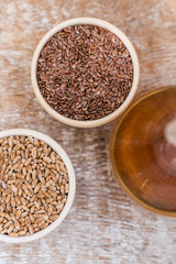 Wooden bowls with flax and wheat grain and oil