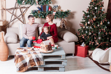 Portrait of young friendly family on Christmas morning. Father, mother and daughter