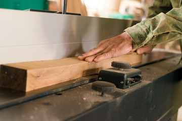 Hand using electric planer and wooden beam