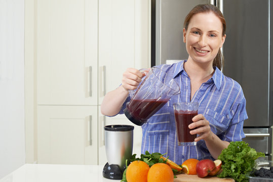 Portrait Of Woman Making Juice Or Smoothie In Kitchen