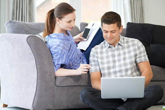 Freelance Couple Working From Home Looking At Laptop Together