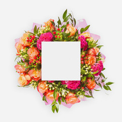 Creative layout made of flowers and leaves with paper card note. Flat lay