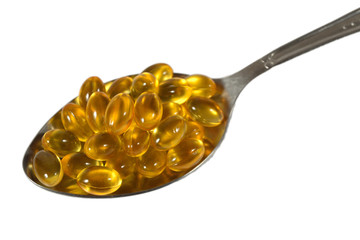 Omega-3 fish fat oil capsules in spoon on a white