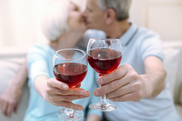 Romantic atmosphere. Two active romantic cute pensioners kissing while holding their drinks