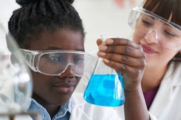 Female Pupil And Teacher Conducting Chemistry Experiment