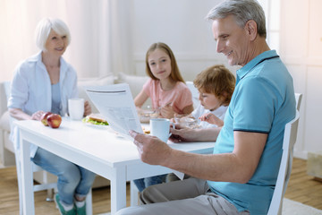 Obraz premium Relaxed morning. Pleasant calm family sitting at the table and eating their tasty breakfast