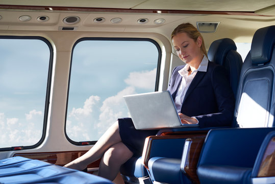 Businesswoman Working On Laptop In Helicopter Cabin During Flight