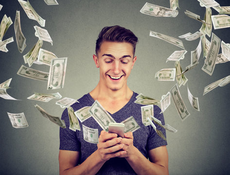 Online banking money transfer, e-commerce concept. Young man using smartphone with dollar bills flying away from screen