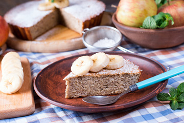 Slice of banana cake on a plate on a wooden background