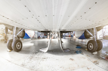 View from under the aircraft between the chassis racks of wheels in the hangar. - obrazy, fototapety, plakaty
