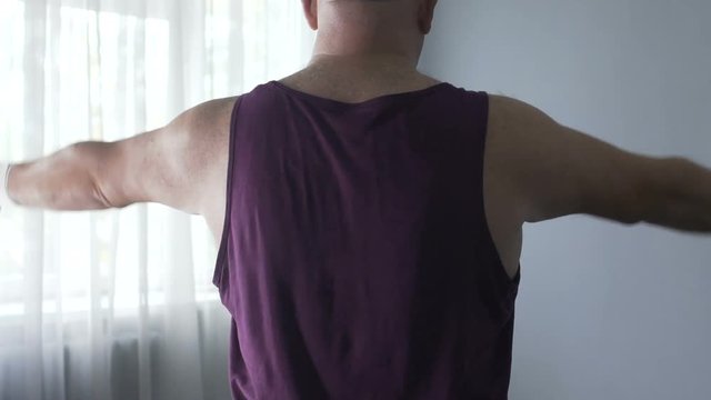 Man doing sports slowly lifting dumbbells in his ward, recovering from injury