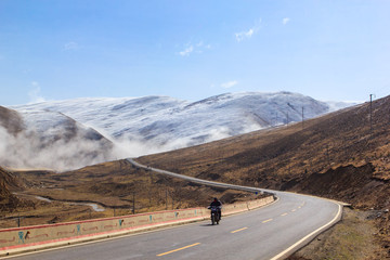 Motorcycle on the road, Beautiful winter road in Tibet under snow mountain, Sichuan, China