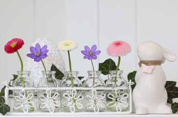  Osterdekoration mit Frühlingsblumen in Pstelfarben in Glasflaschen