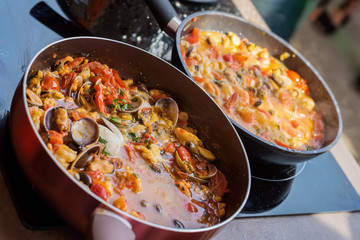 Close-up of frying pans with seafood dish cooked in tomato sauce. Fresh stewed Clams, Shrimps, mussels and squid, base for Italian pasta