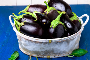 Fresh eggplant in grey basket on blue wooden table.Rustic background. Close up. Vegan vegetable.