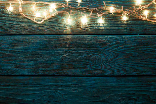 Photo of blue wooden table with burning New Year's garland.