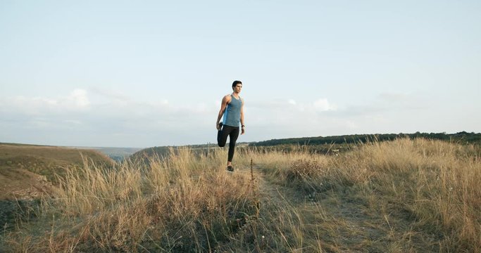 Slow Motion Male athlete exercising outdoors. Sports and active lifestyle. Man running into sunset, colorful sunset sky.