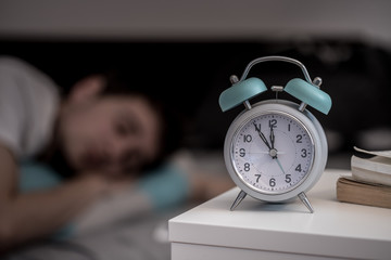 Wecker auf Nachttisch, schlafender junger Mann, entspannt 