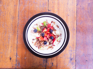 Closeup mixed fruit yoghurt in big bowl,on wooden desk,health food for diet.