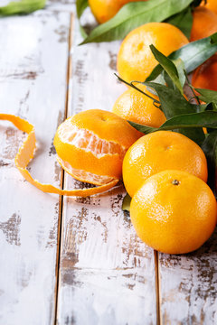 Ripe organic clementines or tangerines with leaves over white wooden plank table as background. Close up, space. Healthy eating