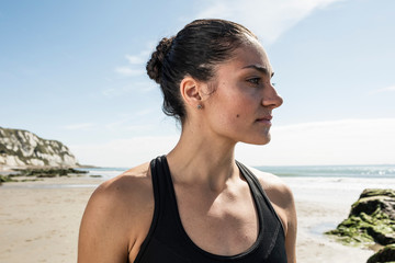 Young female runner gazing from beach