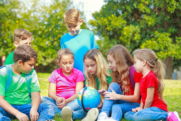 Fototapeta premium Children with a globe are learning geography at the park