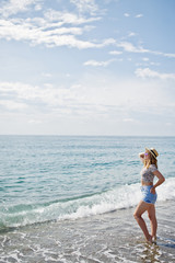 Fototapeta premium Beautiful model relaxing on a beach of sea, wearing on jeans short, leopard shirt and hat.