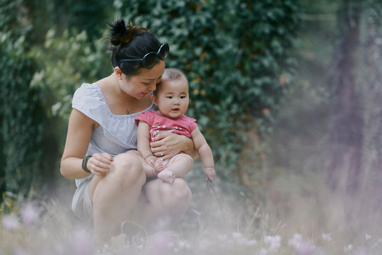 Woman crouching with baby daughter in park, Chenonceaux, Loire Valley, France