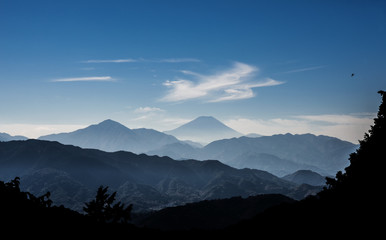 Iconic Mount Fuji wrapped in misty clouds like and old painting, seen from Mount Takao in Japan