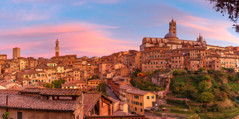 Naklejka na ściany i meble Beautiful panoramic view of Old Town with Dome and campanile of Siena Cathedral, Duomo di Siena, and Mangia Tower or Torre del Mangia at gorgeous sunset, Siena, Tuscany, Italy