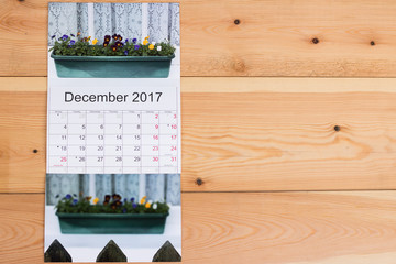 Calendar of December 2017 for a gardener with an image of beautiful violets on a windowsill in a winter season. Space for your great words is on the right on wooden wall.