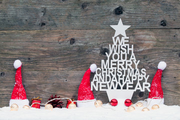 Weihnachtsbaum mit Text Weihnachtsmützen in rot rustikal vor Holzhintergrund