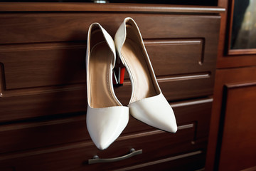 Red women's shoes stand on the windowsill, wedding, boutonniere.